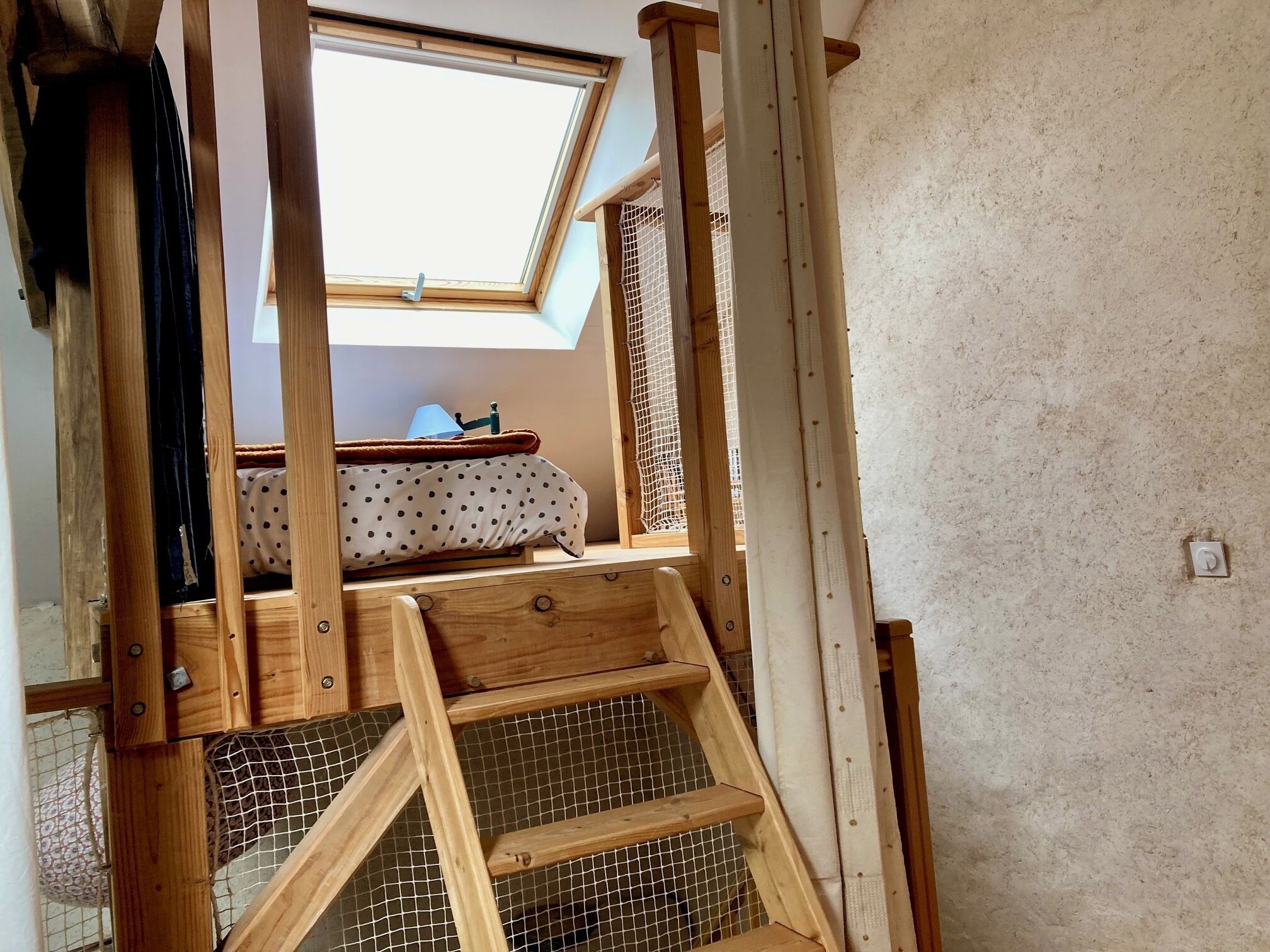 A wooden staircase with a skylight leading to a bed with a polka dot bedspread.