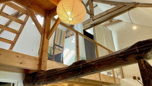 A wooden interior with a hanging spherical light fixture, wooden beams, and a mesh window. - Gite modulable "Chez Yvette", 65m2 au calme à 800 mètres du centre ville (La Gacilly)