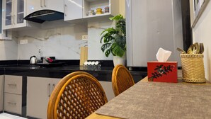 Eine moderne Küche mit weißen Schränken, einer Marmor-Spritzschutzwand und einem Essbereich mit Tisch und Stühlen.