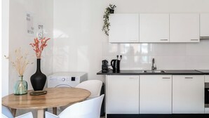 Une cuisine moderne avec des meubles blancs, un évier et un coin repas comprenant une table ronde et des chaises.