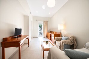 Ein modernes Hotelzimmer mit einem Holztisch, einem Fernseher, einem Sofa, einem Couchtisch und einer Lampe.