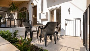 A patio with wicker furniture, a gated entrance, and a building with a number '88' on the wall.