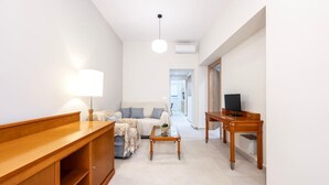 A modern living room with a sofa, coffee table, TV stand, and a lamp.