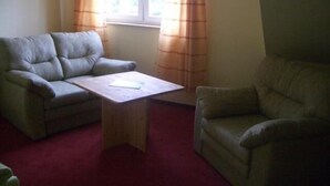 A room with two sofas, a small wooden table, and a window with curtains. - Landhotel zum Honigdieb (Ribnitz-Damgarten)