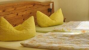A bed with a wooden headboard, two yellow pillows, and a floral-patterned bedspread. - Landhotel zum Honigdieb (Ribnitz-Damgarten)