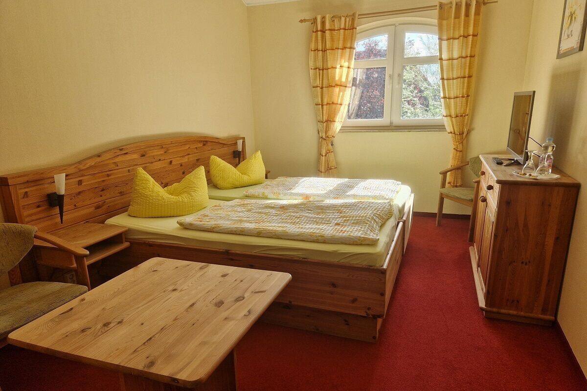 Une chambre à coucher avec un lit en bois, un bureau en bois, une commode en bois et une fenêtre avec des rideaux.