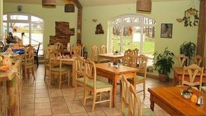 A dining area with wooden tables and chairs, a brick wall, and hanging baskets. - Landhotel zum Honigdieb (Ribnitz-Damgarten)