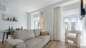 A modern living room with a sofa, a chair, a table with bottles, and a lamp. - Faro Downtown - F in Faro (Faro)
