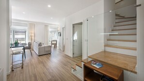 A modern interior with a staircase, a sofa, a dining area, and a glass door leading to another room. - Faro Downtown - F in Faro (Faro)