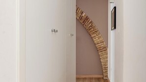 Ein schmaler Flur mit Holzboden, weißen Wänden und einer geschwungenen Holztreppe.