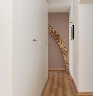 A narrow hallway with a wooden floor, white walls, and a curved wooden staircase. - Charming apartment in Kalsa (Palermo)