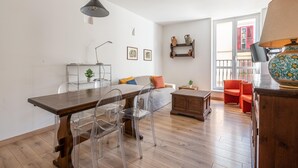 Ein modernes Wohnzimmer mit einem Holzesstisch, klaren Stühlen, einem grauen Sofa und einem roten Sessel.