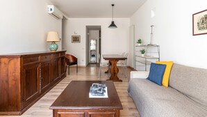 Ein Wohnzimmer mit Holzschrank, einer Couch, einem Couchtisch, einem Esstisch und Stühlen.