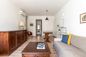 A living room with a wooden cabinet, a sofa, a coffee table, a dining table, and chairs. - Charming apartment in Kalsa (Palermo)