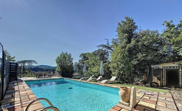 A rectangular swimming pool with a clear blue water surface, surrounded by a wooden deck. There are lounge chairs and umbrellas along the poolside. - Magnificent villa with breathtaking views, a pool, and a hot tub, 35 minutes from the beaches (Bédarieux)