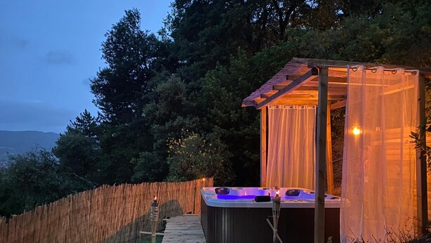 A hot tub with a wooden deck and a covered area, surrounded by a wooden fence and trees. - Magnificent villa with breathtaking views, swimming pool, Jacuzzi 35min from the beaches. (Bédarieux)