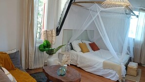 A room with a bed, a sofa, a coffee table, and a decorative plant. - Magnificent villa with breathtaking views, swimming pool, Jacuzzi 35min from the beaches. (Bédarieux)