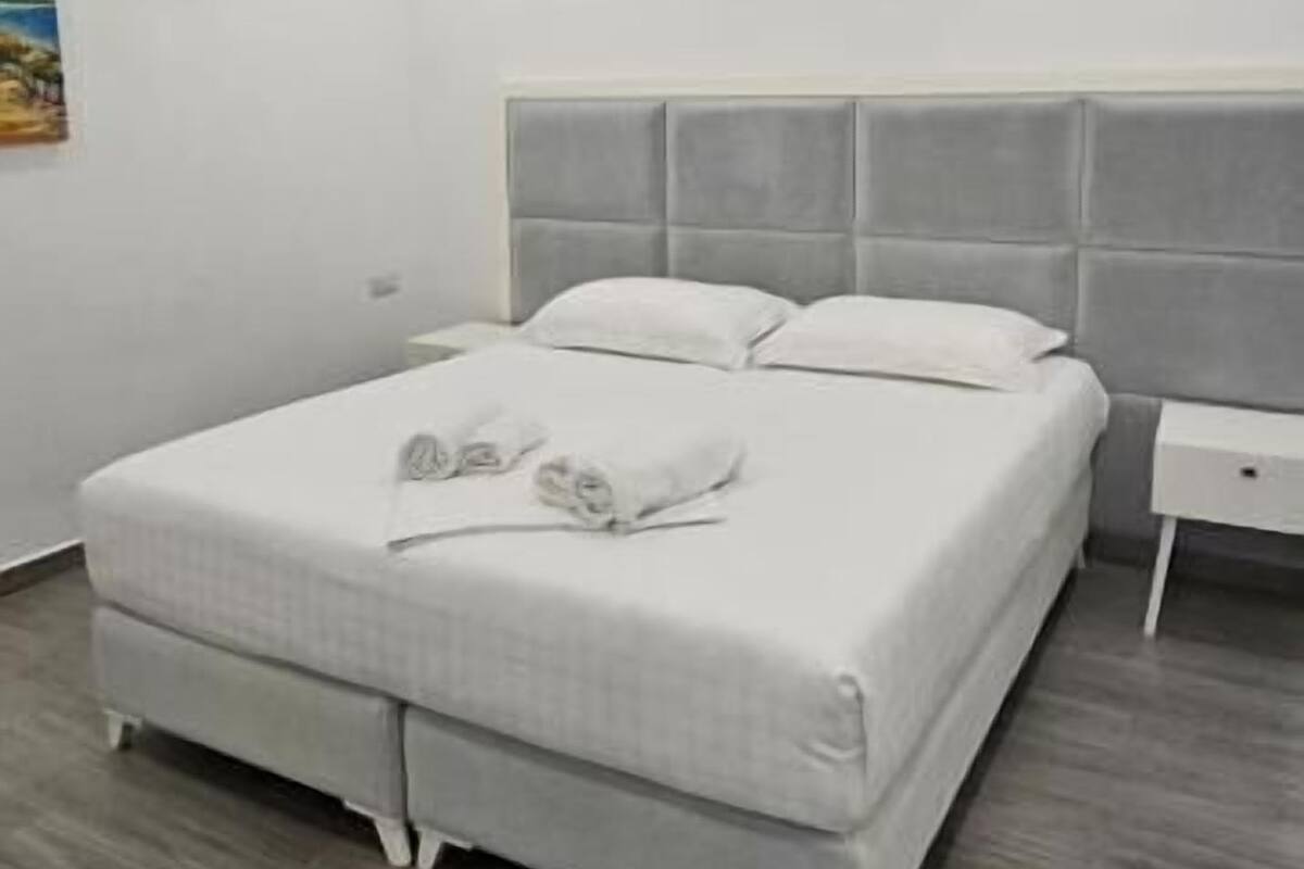 Un dormitori amb un llit, una petita taula de nit i un quadre al mur.