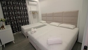 A hotel room with a large bed, two bedside tables, a wardrobe, and a curtain with a pattern. - Hotel Edina by Hp (Sarande)
