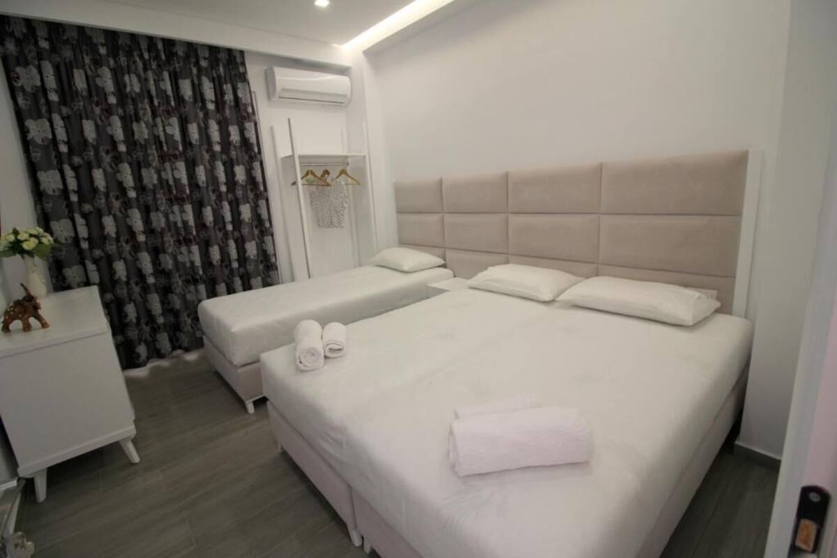 Habitació d'hotel amb un llit gran, dues taules de nit, un armari i una cortina amb dibuixos.