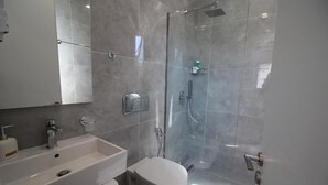 A modern bathroom with a glass shower enclosure, a white sink, and a toilet. - Hotel Edina by Hp (Sarande)