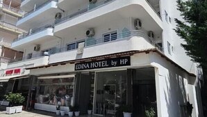 A multi-story hotel with balconies, a sign reading 'EDINA HOTEL by HP,' and potted plants in front. - Hotel Edina by Hp (Sarande)