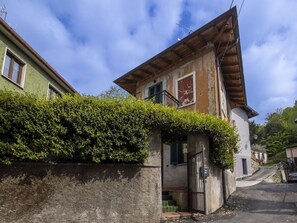 Un immeuble de deux étages doté d’un balcon, d’une entrée sécurisée par un portail et d’un escalier menant à l’entrée.