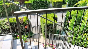 Een metalen hekwerk met uitzicht op een tuin en een gebouw op de achtergrond.