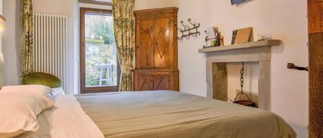 Un dormitorio con cama, armario de madera, televisor y chimenea.