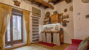 Um quarto aconchegante com teto de madeira, sofá vermelho, cozinha com armários de madeira e janela com cortinas.