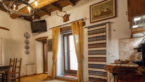 Um interior rústico com pisos de madeira, área de refeições, cozinha com fogão e uma grande janela com cortinas.
