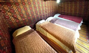 A room with patterned walls, three beds, and a striped floor.