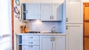 Una cocina con armarios azul claro, una estufa a gas, un lavabo y una puerta de madera.