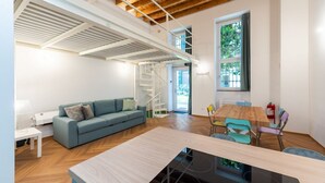 Un interior moderno con techo de madera, un sofá, una mesa de comedor y una escalera.