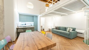 Un interior moderno con una mesa de comedor de madera, un sofá verde y una zona de cocina.
