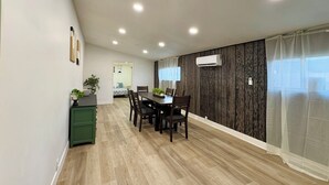 Un coin repas avec une table et des chaises en bois, un meuble vert et une plante en pot.