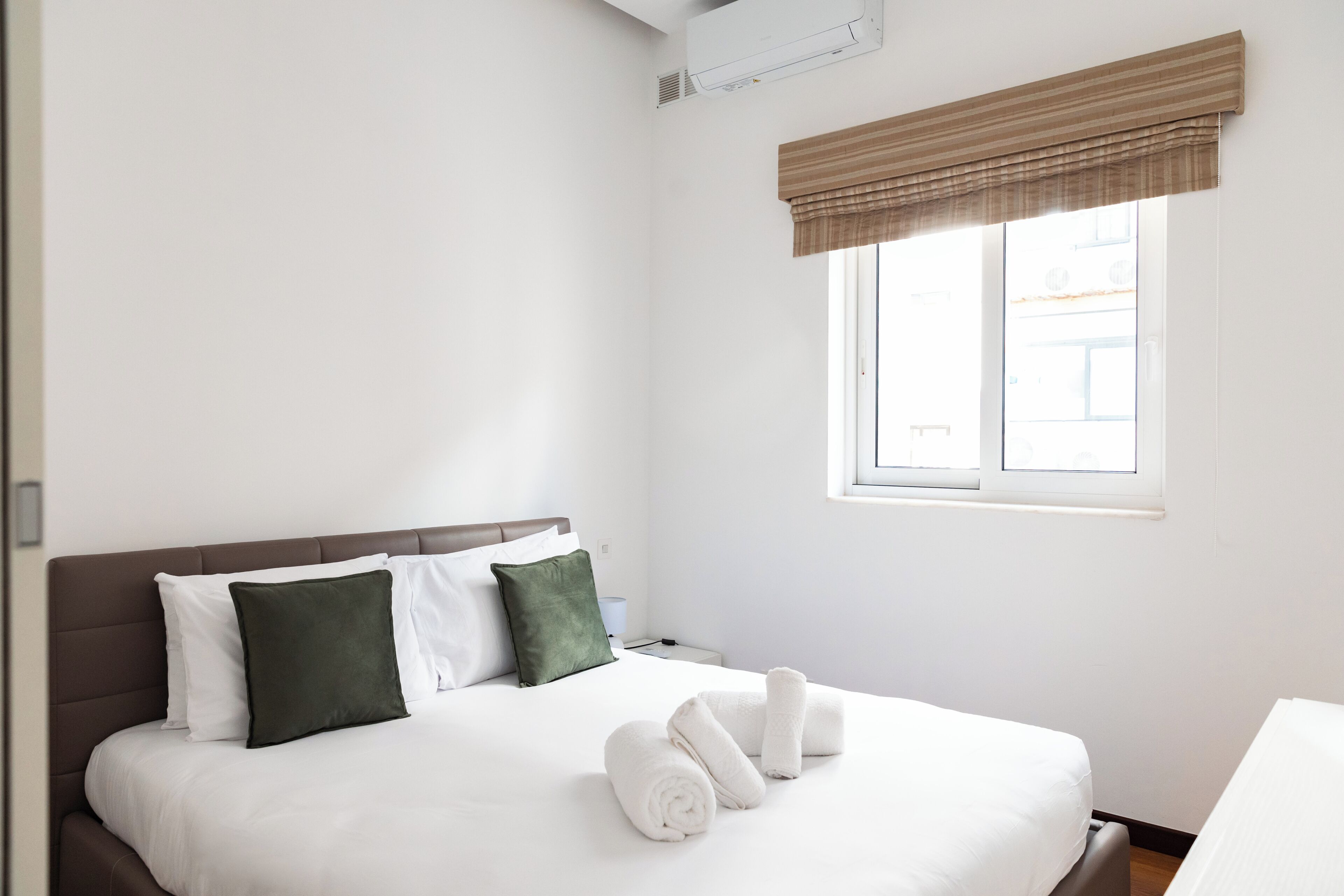 Une chambre d’hôtel avec un lit, des oreillers, une fenêtre et une table de chevet.