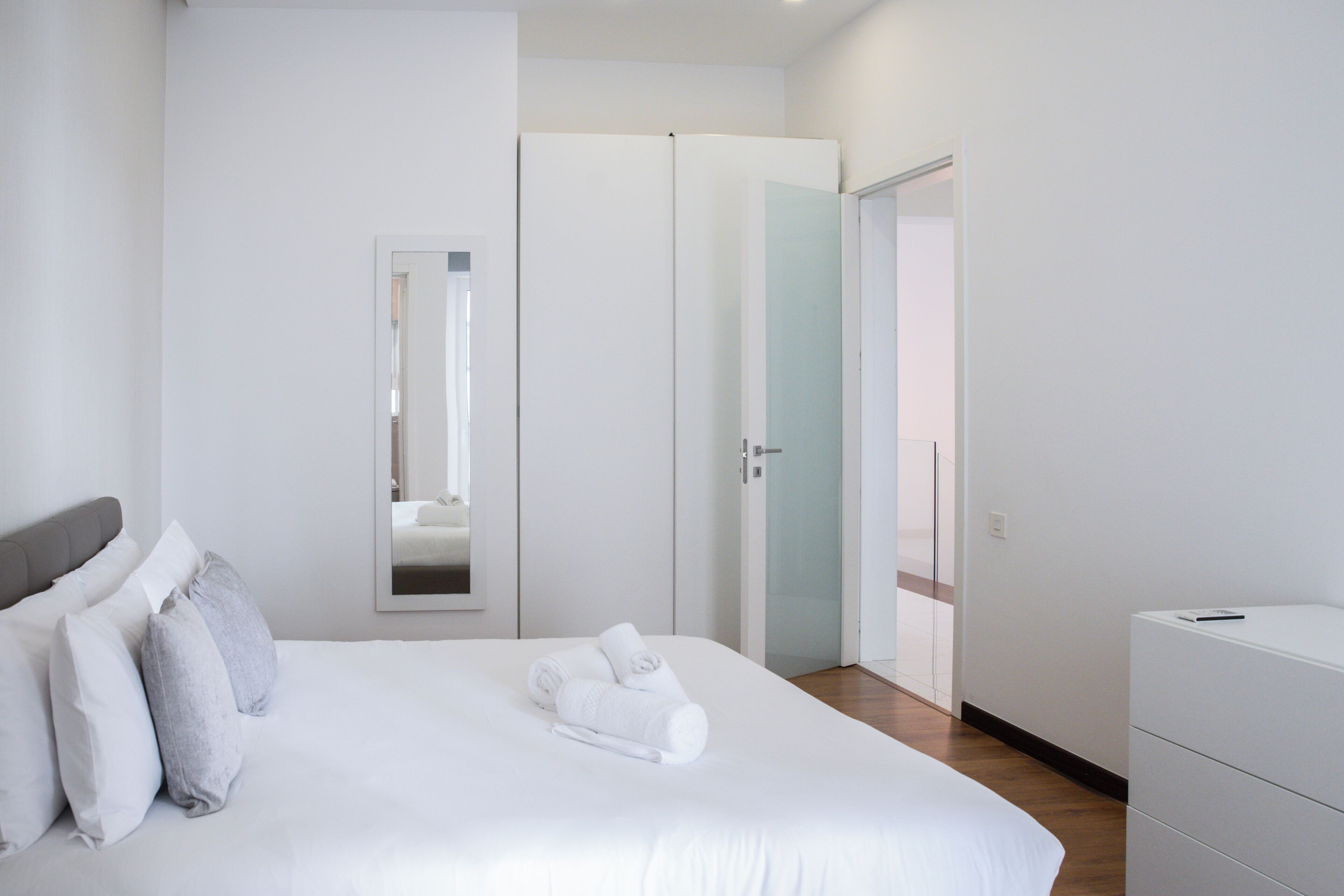 A hotel room with a bed, a dresser, a mirror, and a door leading to a balcony.
