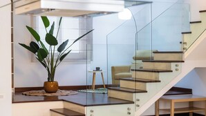A modern kitchen with a glass staircase, a central island, and a potted plant. - Duplex Sliema (Sliema)