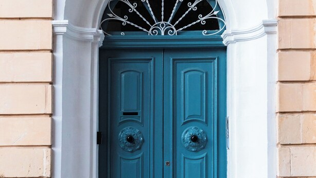 A double door with a decorative metal arch above it, set within a stone wall. - Duplex Sliema (Sliema)
