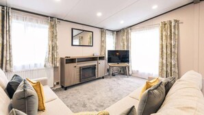 A living room with a fireplace, a television, and a sofa. - Fox Lodge with Hot tub (york)