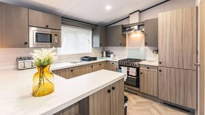 A modern kitchen with a microwave, stove, and wooden cabinets. - Fox Lodge with Hot tub (york)