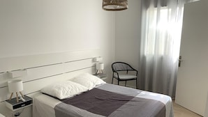 Une chambre à coucher moderne avec un lit, des tables de chevet, une chaise et une fenêtre avec des rideaux.