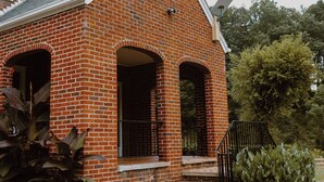 Una casa in mattoni con un camino, un portico e un piccolo giardino.