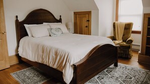 Una camera da letto con un letto grande, una porta in legno, una finestra e una sedia.
