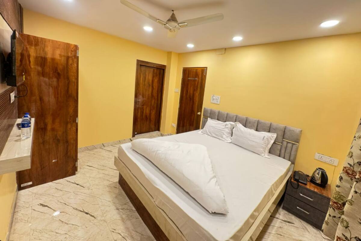 Un dormitorio con cama, ventilador de techo, puertas de madera, suelo de mármol y una botella de agua sobre una encimera.