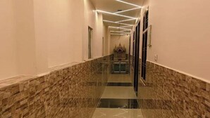 A hallway with a geometric light design on the ceiling, a marble floor with a herringbone pattern, and a stone wall on one side.