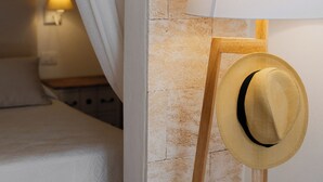 Makuuhuoneessa on sänky, yöpöytä, lamppu ja hattu, joka on asetettu jalustalle.