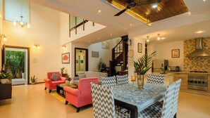 A spacious living area with a dining table, chairs, and a kitchen in the background. - Staymaster Casa Amaira 3BR Villa  (Vagator)