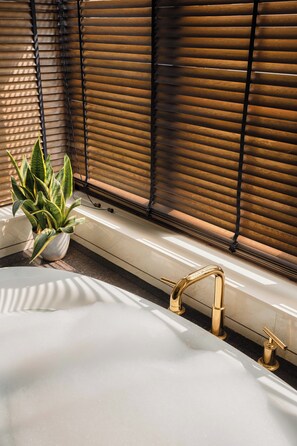 A bathroom with a bathtub, a potted plant, and a window with blinds. - Staymaster Casa Amaira 3BR Villa  (Vagator)